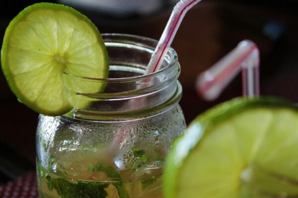 Close-up of a refreshing mojito with lime slices and a straw, perfect for summer.