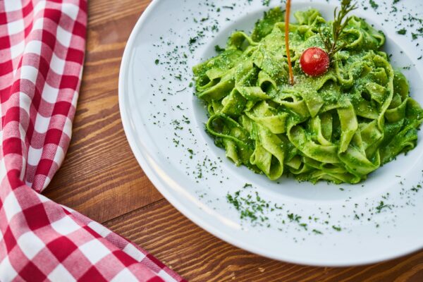 Delicious fettuccine pasta tossed in vibrant green pesto, garnished with a cherry tomato, perfect for an Italian-style meal.