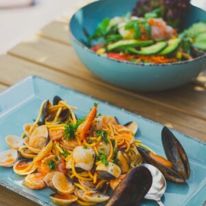 Seafood pasta served outdoors, featuring shrimp, mussels, and fresh vegetables, perfect for food enthusiasts.