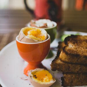 Rustic breakfast scene with soft-boiled eggs in egg cups and freshly toasted bread.