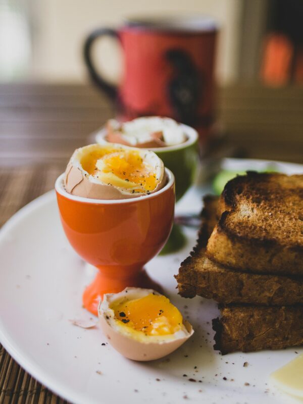 Rustic breakfast scene with soft-boiled eggs in egg cups and freshly toasted bread.