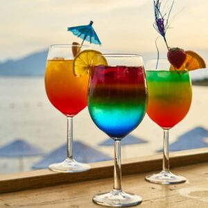 Colorful cocktails with garnishes at a sunset beach bar, perfect for tropical vacations.