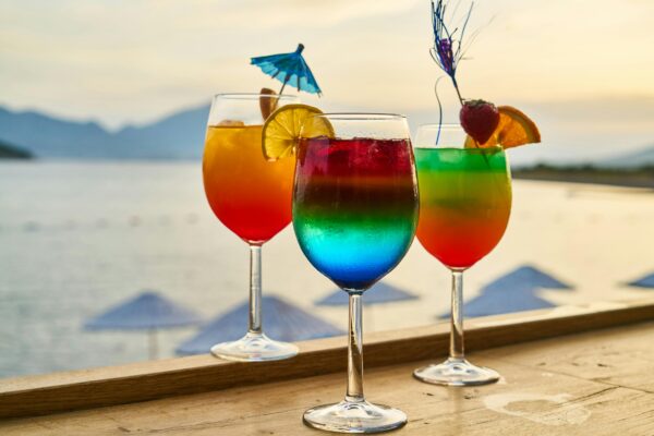 Colorful cocktails with garnishes at a sunset beach bar, perfect for tropical vacations.