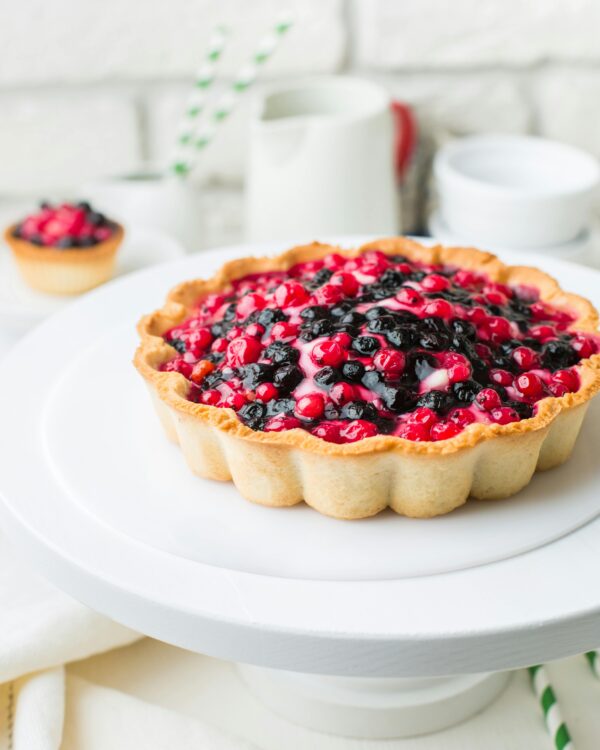 Homemade berry tart with fresh blackberries and currants on a white plate.