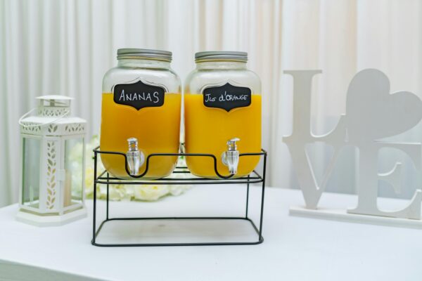 Elegant setup of pineapple and orange juice dispensers in glass jars, perfect for events.