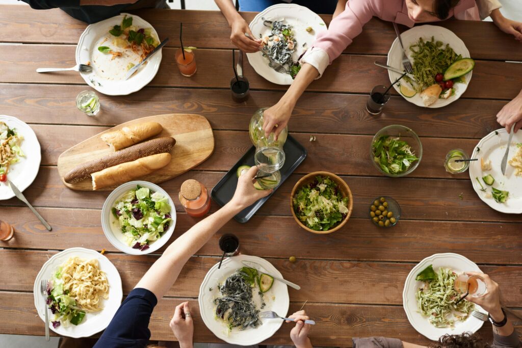 pexels-photo-3184192-3184192 An overhead shot of a dining table featuring various pasta dishes and salads shared by a group.