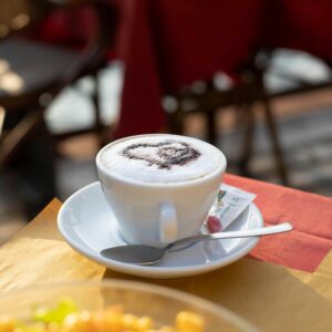 Enjoy a warm Italian cappuccino with a scenic backdrop at an outdoor cafe, perfect for breakfast.