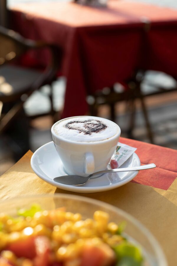 Enjoy a warm Italian cappuccino with a scenic backdrop at an outdoor cafe, perfect for breakfast.