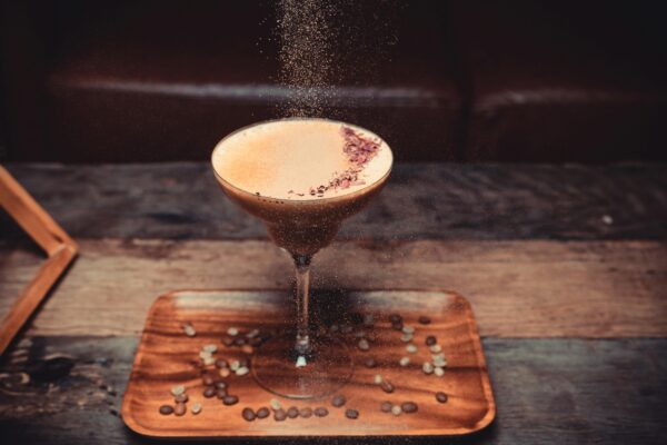 A stylish coffee cocktail dusted with garnish on a wooden tray, perfect for cozy settings.