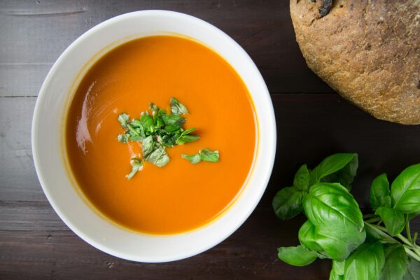 Delicious homemade tomato soup served with basil leaves and rustic bread.