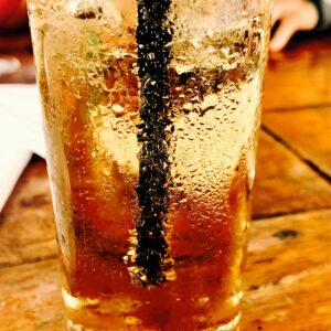 Chilled glass of soda with condensation on a wooden table, perfect for summer refreshment.