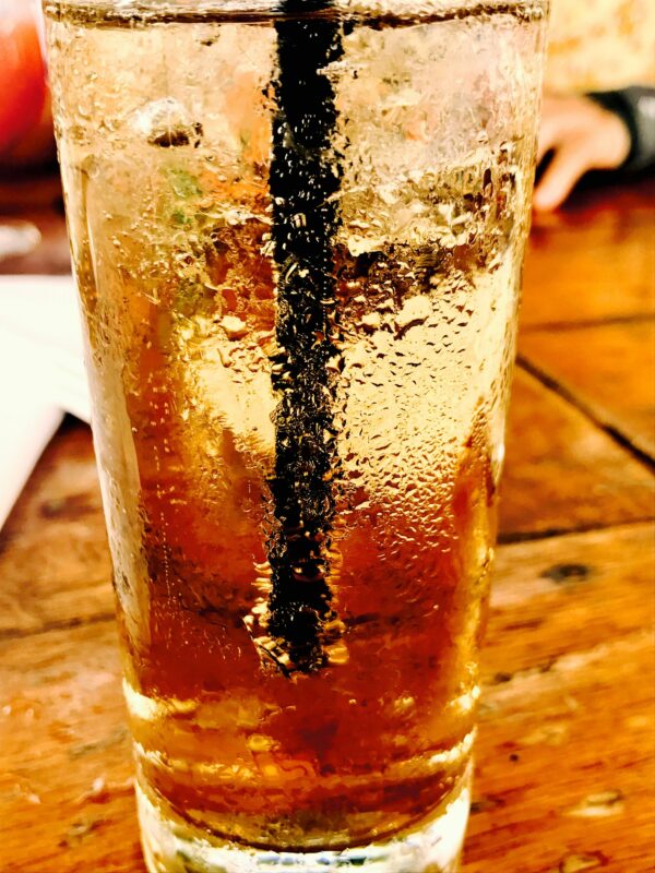 Chilled glass of soda with condensation on a wooden table, perfect for summer refreshment.